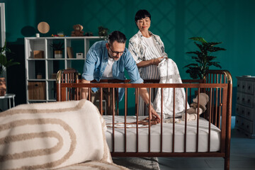 Expecting parents preparing baby's crib in cozy nursery