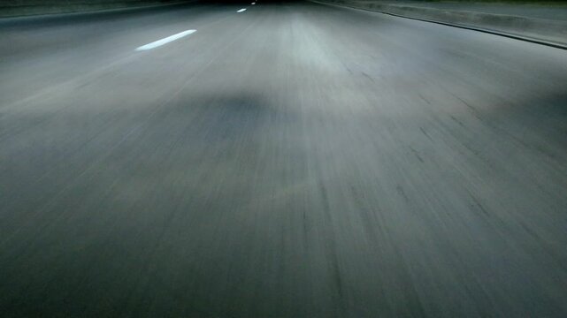 Low angle POV asphalt road with lane markings. Night