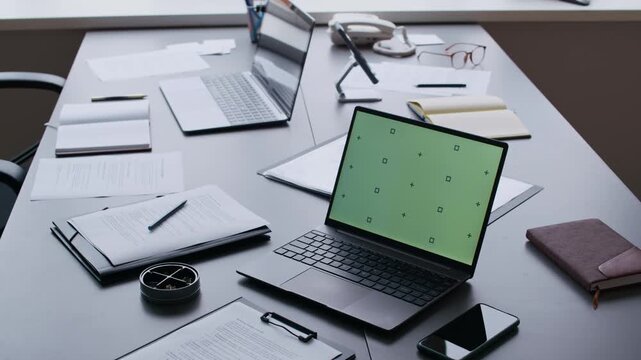 Workplace of office managers or other coworkers with two laptops, folders and clipboard with paper documents, smartphones, pens, notepads, eyeglasses and telephone