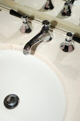 Modern bathroom sink with chrome faucet and handles on marble countertop

