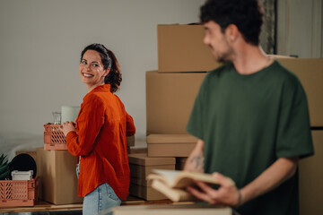 Couple moving into new home carrying boxes and smiling
