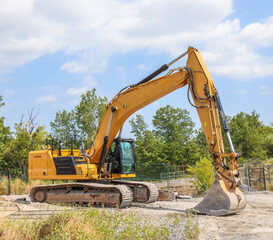 Large yellow hydraulic bucket excavator sitting in a construction site, nobody