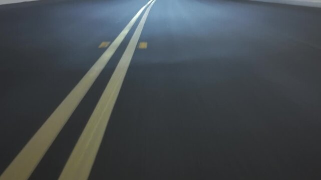Low angle POV asphalt road with lane markings. Night
