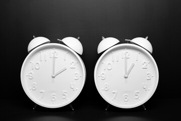 Daylight saving time concept. Two White Retro clock isolated on black background. Copy space