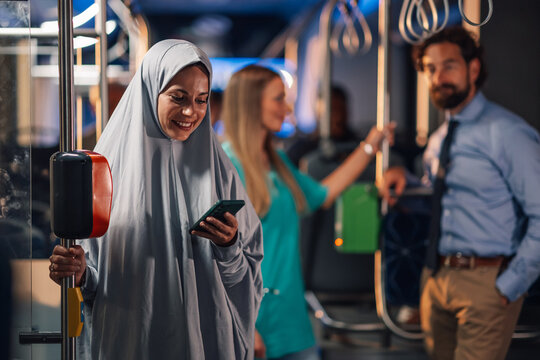 Muslim woman using smartphone on public transport - Powered by Adobe