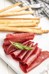 Slices of smoked bresaola on white table.