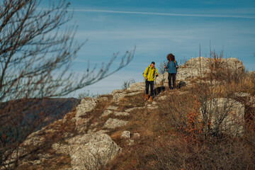 Obraz premium Hikers walking up rocky mountain trail on sunny autumn day