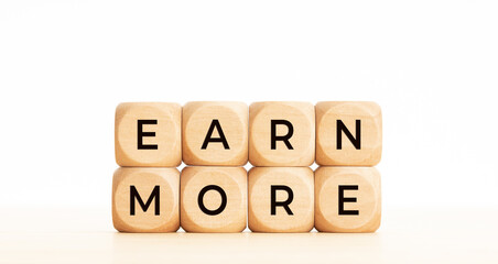 Earn more phrase on wooden block shape. Copy space. White background
