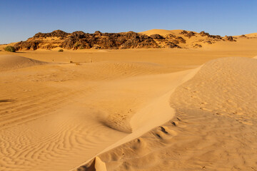 Sahara desert landscape. Small sand dunes and rocks. Erg Admer near Djanet, Algeria
