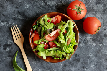 Salad bowl with green lettuce, tomato, baby spinach, pomegranate and almond. Vegetarian food and healthy eating. 