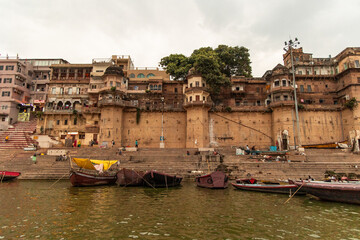 Naklejka premium Wooden Boats Floating on Ganges River with Varanasi Ghats in Background