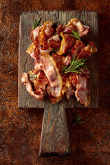 Fried bacon with rosemary on an old cutting board.