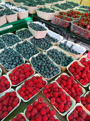 Fresh raspberries, blueberries and cherries displayed at a market stall