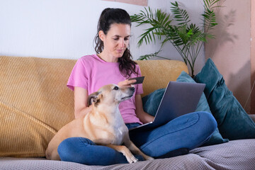 Obraz premium Woman doing online shopping with her dog on sofa