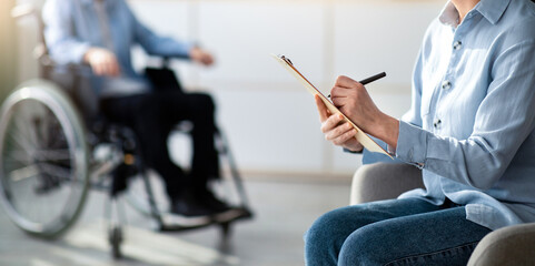 Fototapeta premium Female psychologist working with handicapped adolescent in wheelchair at office, copy space. Unhappy disabled teenager having consultation with psychotherapist at clinic, selective focus