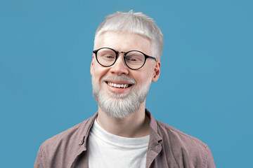 Headshot portrait of happy albino blond man with pale skin wearing eyeglasses, looking and smiling...