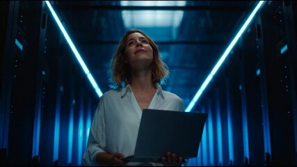 IT manager conducts diagnostics and system checks in a modern server environment. She holds a laptop displaying diagnostic software. - Powered by Adobe