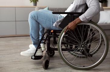 Obraz premium Lifestyle person with disabilities, problems, care and recovery at home and in clinic. Adult 40s african american male in wheelchair, in living room interior, cropped, free space, side view
