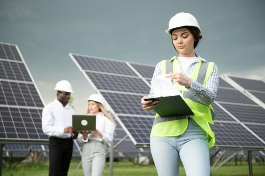 Male and female engineers worker working in solar panels power farm. technician working at solar power station - Powered by Adobe