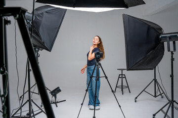 Model posing in a studio surrounded by professional lighting equipment and camera setup during a fashion photoshoot