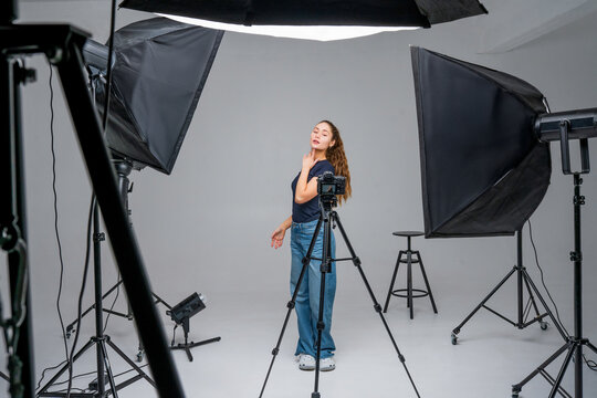 Model posing in a studio surrounded by professional lighting equipment and camera setup during a fashion photoshoot