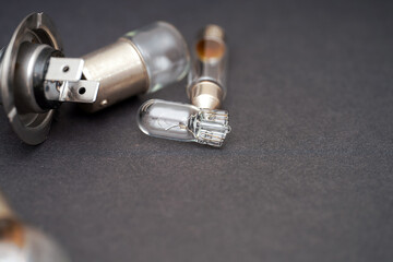 Close-up view of various glass bulbs and metal bases used in lighting components on a dark background