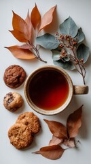 Cozy autumn tea time with cookies and colorful leaves arranged on a light background