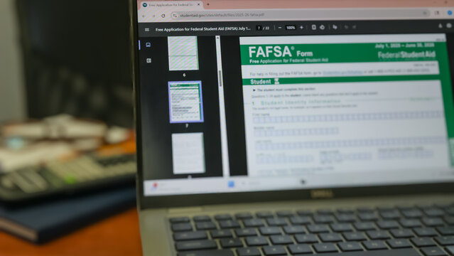 A laptop displaying the FAFSA Form (Free Application for Federal Student Aid) and desk background. College preparation and higher education design ele