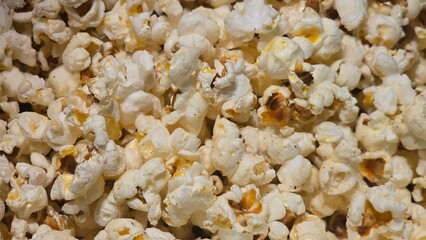A close-up of a large pile of freshly made popcorn, with some kernels showing hints of a brown or buttery finish.