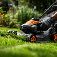 A black and orange lawn mower with an electric motor is being used to cut the grass on the lawn The hand of someone wearing gloves is holding onto it in a clo.