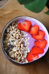 Healthy acai yogurt bowl with strawberries, cereals and white chocolate drops, fresh breakfast food beautifully presented