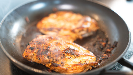 Seasoned chicken fillet sizzling in a frying pan, cooked to a golden brown with herbs and spices. Perfect for healthy eating content, quick dinner ideas, or home cooking blogs. Close-up shot with stea