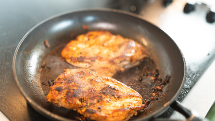 Seasoned chicken fillet sizzling in a frying pan, cooked to a golden brown with herbs and spices. Perfect for healthy eating content, quick dinner ideas, or home cooking blogs. Close-up shot with stea