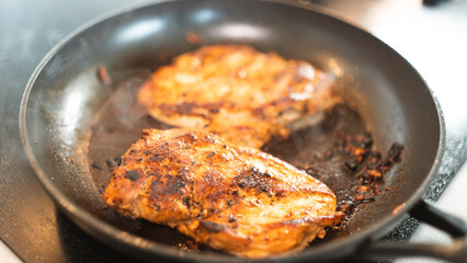 Seasoned chicken fillet sizzling in a frying pan, cooked to a golden brown with herbs and spices. Perfect for healthy eating content, quick dinner ideas, or home cooking blogs. Close-up shot with stea