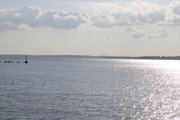 Peaceful Coastal View With Sailboats on Calm Water Under Partially Cloudy Sky During Golden Hour at Sunset