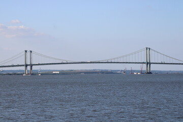 View of a Modern Suspension Bridge Spanning Across a Calm Body of Water Under a Clear Sky, Showcasing Engineering Marvel Against a Peaceful Landscape