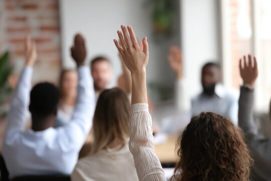 Millennial business leaders and CEOs at an office seminar in a boardroom Participants both men and women raise hands in unity and agreement with a close up on one person s back