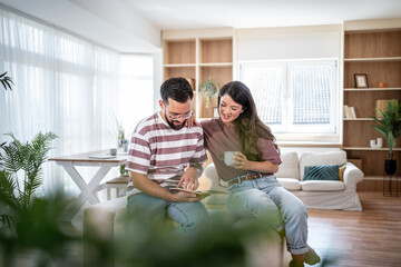 Happy couple browsing digital tablet at home, enjoying relaxing morning