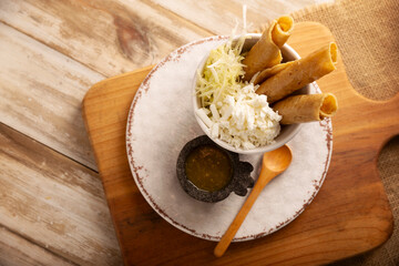 Flautas Ahogadas (Drowned Flautas) Golden tacos made with fried corn tortillas, filled with chicken or beef, and served in a glass or cup containing salsa or broth, lettuce, sour cream, and cheese.