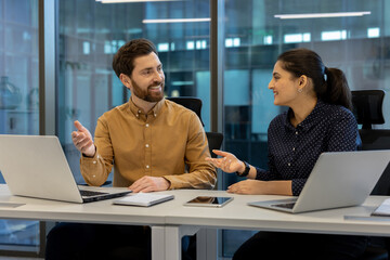 Two colleagues in a modern office having a productive discussion.