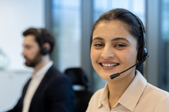 Smiling customer support representative with headset working in a modern office