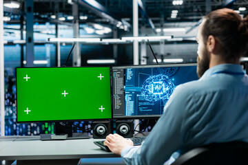 Engineer in data center managing AI training datasets using isolated screen PC monitor. Man using mockup PC display to oversee machine learning in server room supporting scalable infrastructure for AI