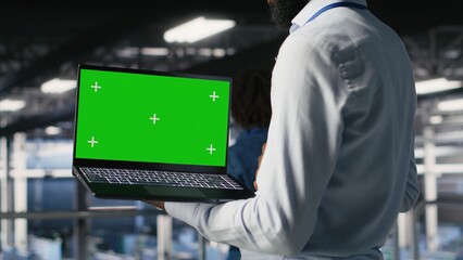 Close up of engineer on data center industrial platform analyzing performance outputs on green screen laptop. Server room IT expert finetuning server rig configurations using mockup notebook