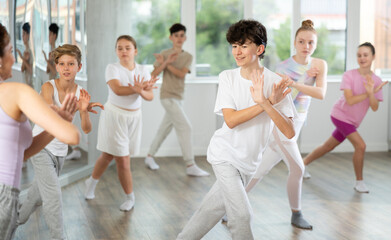Teenage boy rehearse hip hop dance repeats movements of unrecognizable instructor performance with peers. Preparing for performance of choreographic team, practicing skills, repeating exercises