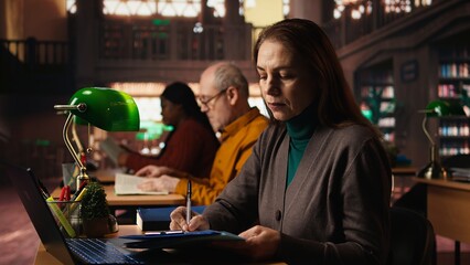 Senior adult learner studying with online academic materials on laptop, collecting important information for exams and thesis completion. Old man serious about graduating college.