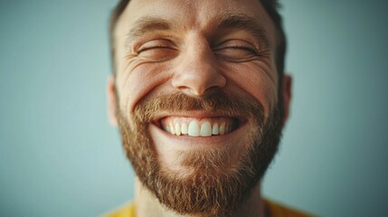 Fototapeta premium A joyful man with a well-groomed beard smiles broadly, radiating happiness and positive energy. His expression captures a moment of genuine joy and warmth.