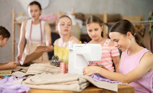 Child watches classmates work on creating clothes, school for young fashion designers and tailors. Optional classes for younger students, professional orientation, and familiarization with profession.