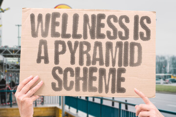 Wellness is a pyramid scheme critiquing commercialized self-care and profit motives. CORPORATE. FRAUD. ILLUSION. HIERARCHY. PRESSURE. MONEY. EXPLOITATION.