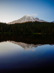Calm Reflection Lake with mirror-like surface reflecting surrounding mountains and trees. Serene nature scene perfect for outdoor and landscape photography.