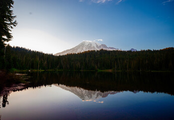 Calm Reflection Lake with mirror-like surface reflecting surrounding mountains and trees. Serene nature scene perfect for outdoor and landscape photography.